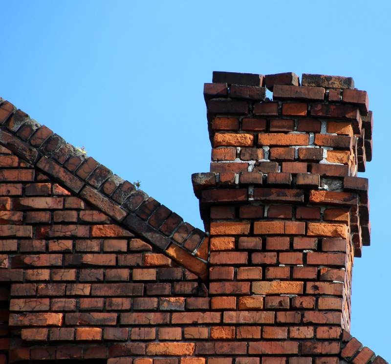 Damaged chimney on an Carrollton home showing cracks and missing mortar